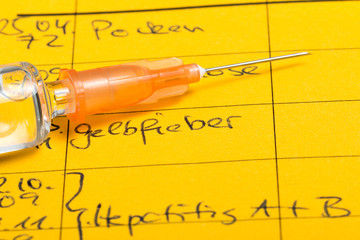 Syringe with vaccine, on vaccination certificate