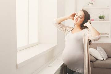 Pregnant woman listening music in headphones