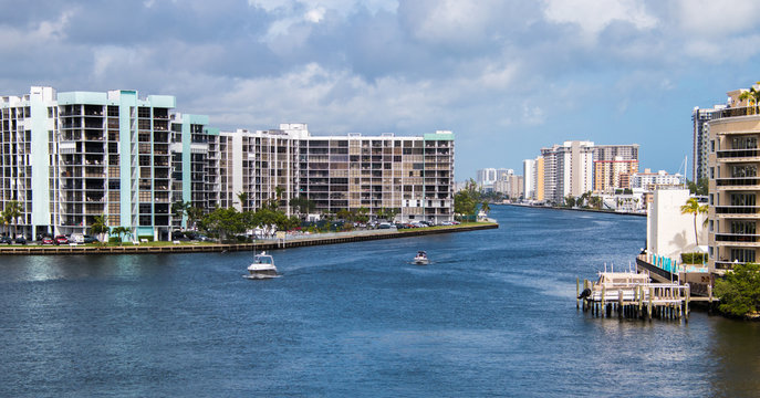 View of intercoastal waterway with boats and blue water. Condominium buildings. Cloudy sky