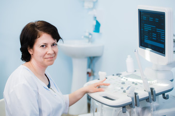 Happy mature female doctor using ultrasound scanner. Echography machine