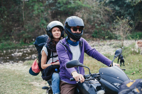 Couple of motor travellers wearing helmets driving motorcikle in mountains