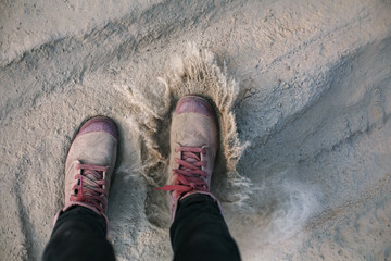 Fototapeta premium Pink sneakers, female legs doing steps on dusty sand road. Off road, long real modern travel concept.