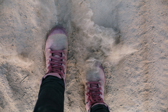 Pink sneakers, female legs doing steps on dusty sand road. Off road, long real modern travel concept.