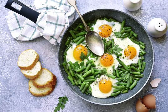 Healthy vegetarian breakfast : fried eggs and asparagus bean in a skillet.Top view.