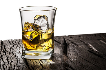 Whiskey glass or glass of whiskey with ice cubes on table at the white background.