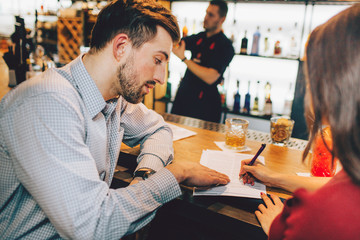 A picture of business metting of two people. Young woman signs the documents that the man gave her to sign.
