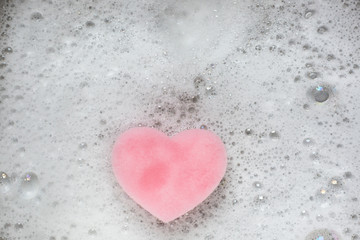 Pink heart sponge in the used sink full of foam