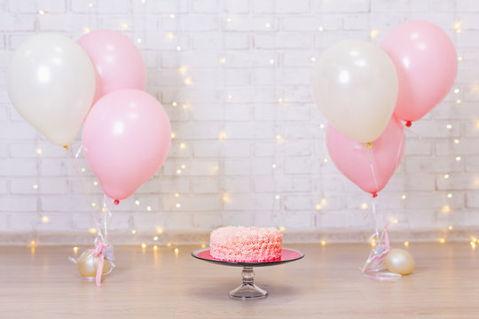 birthday celebration background - cake over brick wall with lights and balloons
