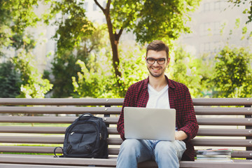 Happy man is using laptop in the park