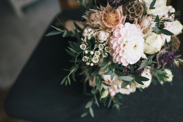 Rustic wedding bouquet with white dahlias, peonies, and greens on a dark chair. Artwork - 199021544