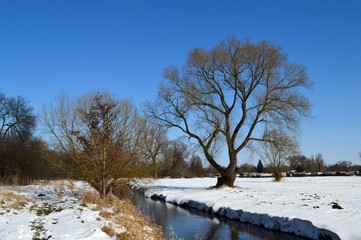 Naklejka na ściany i meble winter landscape with snow, trees, river (parthe), ice and blue sky, Leipzig - Germany, March 2018