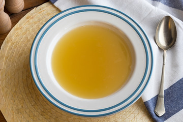 Chicken bone broth served in a plate, top view
