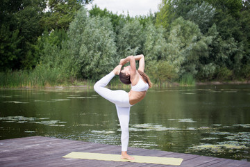 Young girl practices yoga on the shore of the lake, the concept of enjoying privacy and concentration, sunlight