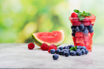 Plastic cup full of fresh cut fruits and berries
