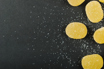 Marmalade. Yellow orange sweets, candy sprinkled with sugar on a black background. Background, copy space, top view