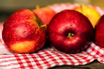 Whole ripe red apples on checked tablecloth close