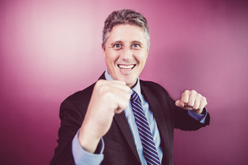 Closeup of smiling middle-aged business man looking straight and punching at camera. Isolated front view on purple background.