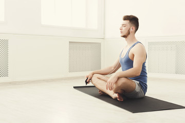 Man training yoga in lotus pose, copy space