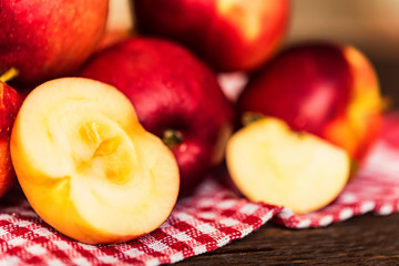 Whole and cut red apples on checked tablecloth