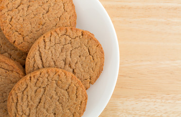 Top close view of several brown sugar and cinnamon cookies on a plate atop a wood table.