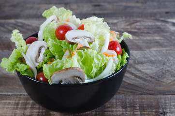 Bowl of salad on rustic wooden background.
