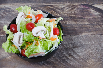 Bowl of salad on rustic wooden background.