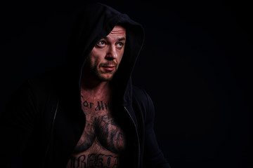 Muscle brutal athlete with tattoos posing in the studio and performing physical exercises