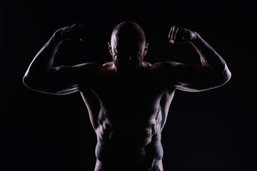 Fototapeta na wymiar Muscle brutal athlete with tattoos posing in the studio and performing physical exercises