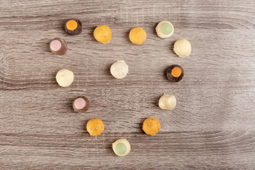 Tasty candies in heart shape for gift on wooden background