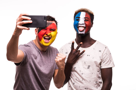 Football fans supporters with painted face of national teams of France and Germany take selfie isolated on white background