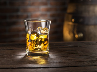 Whiskey glass or glass of whiskey with ice cubes on the wooden background.