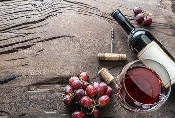 Schilderijen op glas Wijnglas, wijnfles en druiven op houten ondergrond. Wijn proeven. © volff