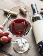 Wine glass, wine bottle and grapes on wooden background. Wine tasting.