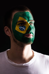 Face portrait of happy fan support Brazil national team with painted face isolated on dark background