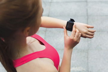 Young woman using smart watch, brick wall