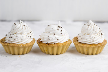 three cupcake with cream decorated with chocolate chips concrete background