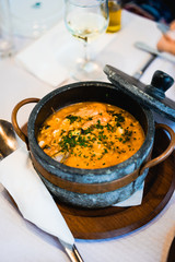National cuisine of Cape Verde: Cachupa in traditional stone bowl. Stone lid laying beside.