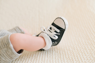 Feet of a newborn baby sneakers, selective focus