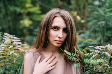 Portrait of beautiful caucasian girl in green leaves. Soft focus