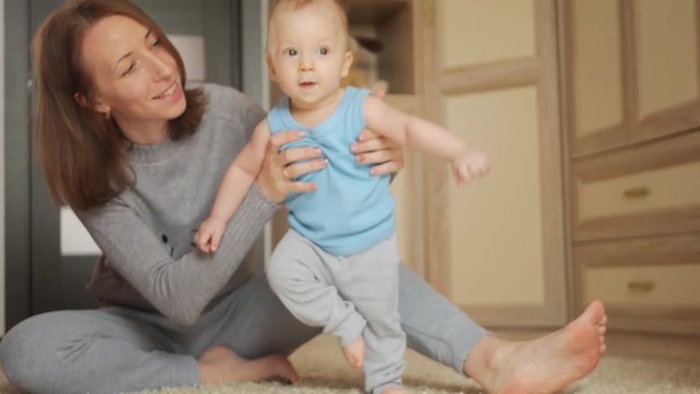 baby taking first steps with mother help