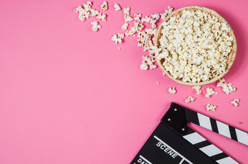 Fresh popcorn and movie clip isolated on pink background top view with copy space around products....