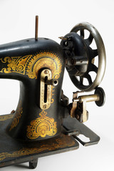 Detail of an old antique sewing machine, decorated with golden ornaments.