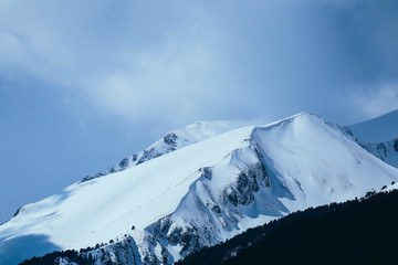 Mountain snow peak, beautiful natural winter backdrop. Ice top of the hill, blue sky background. Alpine landscape.