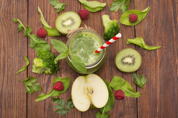 healthy green smoothie with banana, spinach, avocado and kiwi in a glass bottles on a rustic