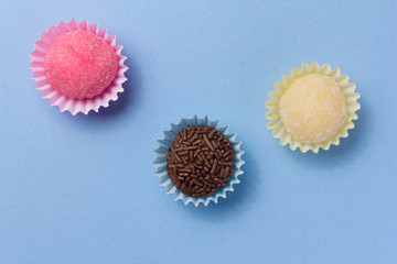 Brigadeiro Beijinho and Bicho de Pe: sweets from Brazil. Child birthday party. Overhead of candy ball on blue table.