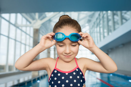 Content Pretty Kid Preparing To Put On Goggles And Jump Into Water But Hesitating Because Of Fear And Looking At Water In Pool