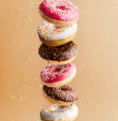 set of different donuts flying in the air along with decorative powder