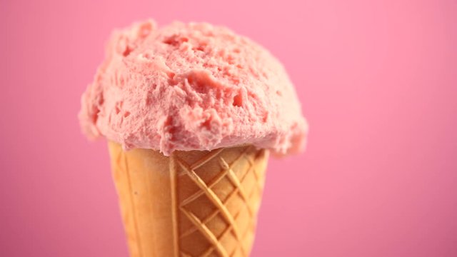 Ice cream. Strawberry or raspberry flavor icecream in waffle cone rotated over pink background. Sweet dessert closeup. 4K UHD video footage. 3840X2160
