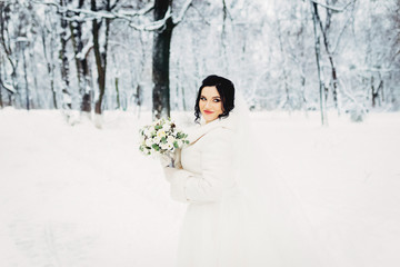 Portrait of an amazing bride. Bouquet, snow, winter.