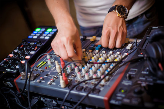 DJ's hands behind the DJ's remote control